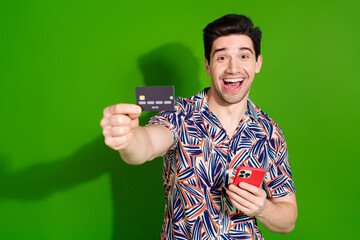 Photo of ecstatic guy with stylish haircut dressed print shirt hold smartphone show you credit card...