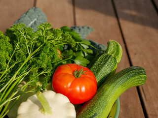 Bowl filled with newly harvested produce. Home grown and organic vegetables. Tomatoes, zucchini, parsley, flowers, apples, pears, beans, peppers, chillies and kale.