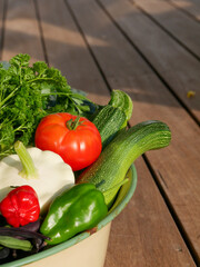 Bowl filled with newly harvested produce. Home grown and organic vegetables. Tomatoes, zucchini, parsley, flowers, apples, pears, beans, peppers, chillies and kale.