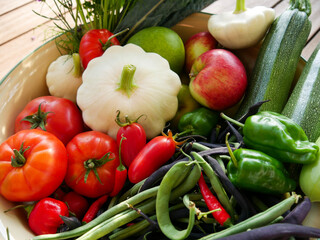 Harvest basket. Home grown vegetables, fruits and flowers just harvested. Fresh produce. Apples, pears, tomatoes, zucchini, beans, parsley, flowers, peppers, and chillies.