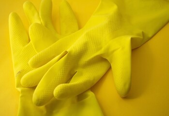 a pair of two yellow gloves for cheaning in an orange background 
