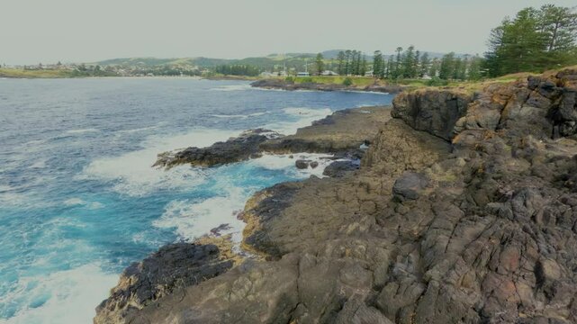 Footage of waves crashing against rocks and a whale breaching offshore near the coastal town of Kiama in the Illawarra region of New South Wales, Australia.