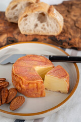Rond des Vignes washed-rind cheese with.ivory-orange rind, strong nose with aromas, French soft cheese with orange rind