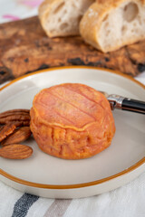 Rond des Vignes washed-rind cheese with.ivory-orange rind, strong nose with aromas, French soft cheese with orange rind