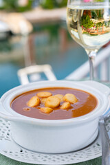 Homemade tasty fish or bisque soup with croutons served with glass of cold white wine and view on...
