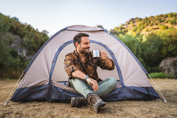 Adult caucasian man drink coffee sit in front tent on camping trip © Miljan Živković