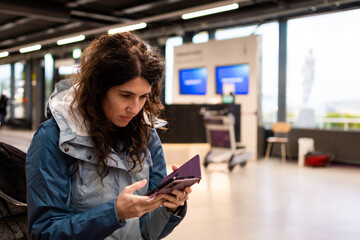 Woman checking her phone and passport at airport terminal