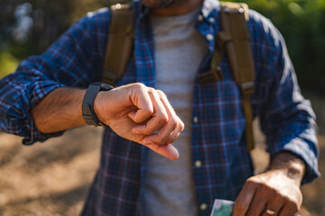 Close up of adult man hiker stand and check time on his wrist watch