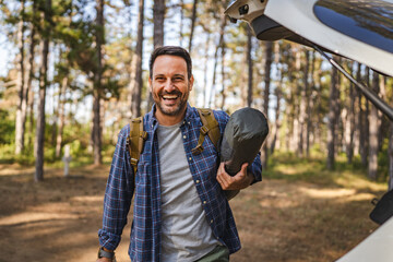 Obraz premium Portrait of adult man hold camping gear near car, ready for camping