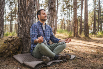 Obraz premium Adult man camper practice meditation and breath exercise in front tree