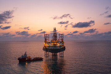Aerial view of silhouette offshore jack up drilling rig during sunset - oil and gas industry.