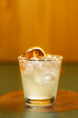 A shot glass with a drink and an orange slice on a table