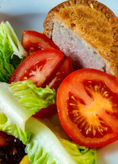 Traditional Pork Pie,close-up and cut into segments with a backdrop of English mustard,sweet pickle and salad.