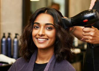 Gorgeous indian young woman getting her hair blow dried at a salon
