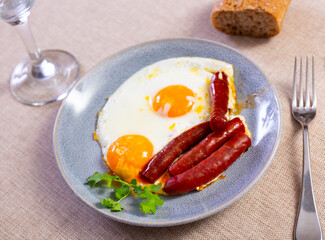 Delicious fried eggs with chistorra sausage served on platter for breakfast