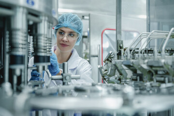 Quality Assurance Engineer. Caucasian female factory worker inspecting quality in professional uniform working of drinking water bottling plant or drinking Water line production