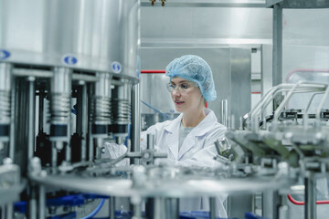 Quality assurance officer – validation. Caucasian female factory worker inspecting quality in...