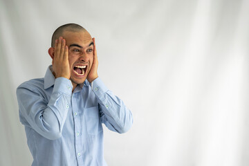 Young man screaming with his hands on his head. Agitated, angry and furious boy shouting very loudly