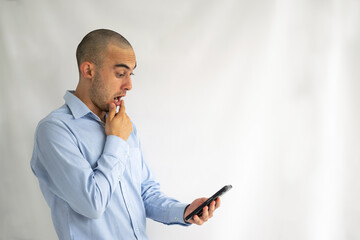 Impressed and shocked bald man looking at his cell phone screen