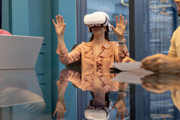 Using VR headset, woman interacting with virtual environment in office meeting