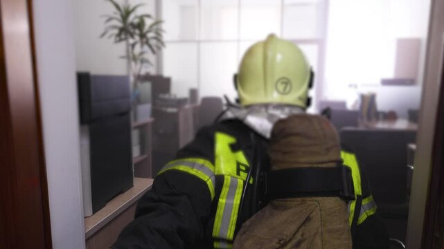 Group of firefighters in protective uniform during fire fighting operation inside the office building corridor, firemen brigade during fire drill, emergency and rescue service, exercise and training