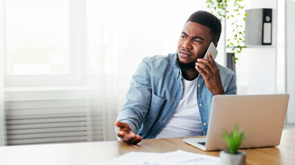 Failure and crisis concept. Upset african american employee getting bad news on phone while sitting...