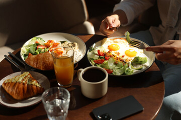 Man having tasty breakfast at wooden table in cafe, closeup