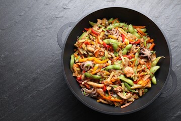 Stir-fry sea food in wok on grey textured table, top view