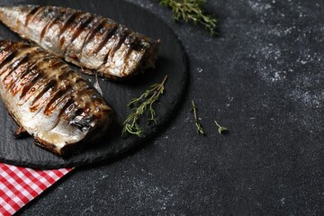 Delicious grilled mackerel, thyme and napkin on dark textured table. Space for text