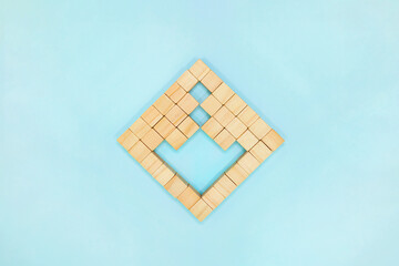 水色の背景でウッドキューブを並べたブロックから下向きの矢印の形を取り除いたマーク