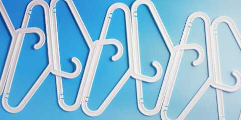 White Plastic hangers as minimal pattern on blue gradient background, banner, Clothes rack for organizing clothes in closet or retail stores for hanging of garments, fashion, organization concept