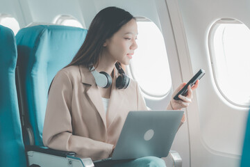 Asian woman on plane airplane window Using a mobile phone while talking on a smartphone, a person talks about his business.