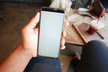A person is holding a smartphone while sitting in a cozy coffee shop environment