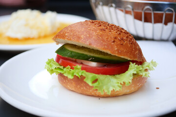 A colorful Vegetable Mini Burger on a plate, topped with crisp lettuce and fresh vegetable slices