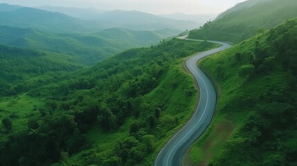 Fototapeta premium Asphalt road way in green forest mountain valley aerial view