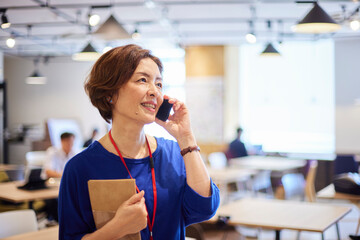 オフィスでスマートフォンで電話をする日本人ビジネスウーマン