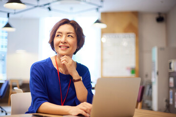 オフィスにてノートパソコンで仕事をする日本人ビジネスウーマン