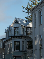Row of traditional white painted houses in northern part of downtown, with sun highlights and wooded ornament details in exterior