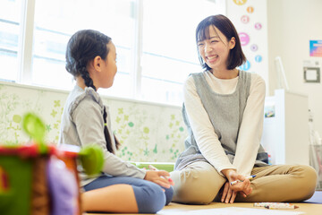 託児所でおもちゃで子供と遊ぶ保育士の女性