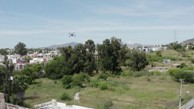 Aerial images following a drone as a protagonist through the country side in Zapopan Mexico, the drone flies over the suburbs, the field and the mountains while another drone follows the black drone