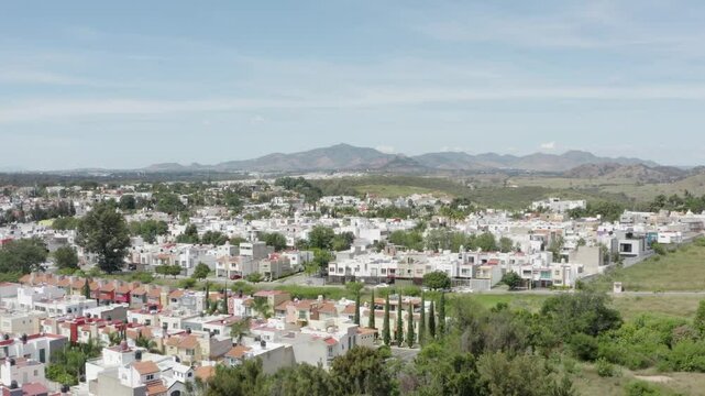 Aerial images following a drone as a protagonist through the country side in Zapopan Mexico, the drone flies over the suburbs, the field and the mountains while another drone follows the black drone