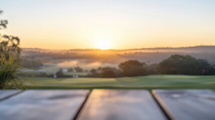 Fototapeta premium The wooden table offers a tranquil view of the golf course at sunrise, capturing the beauty of the dawn light across the landscape