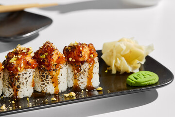 Seared Salmon Sushi Rolls with Pistachio Garnish on Black Plate in Minimalist Light Setting