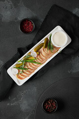 Elegant Presentation of Veal Tongue with Horseradish Sauce and Cornichons on Modern Black Slate Background