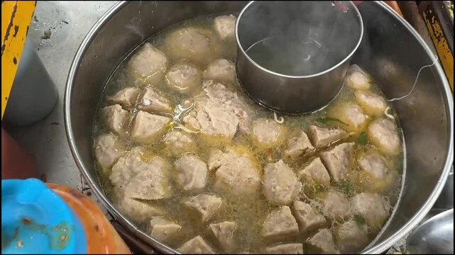 cooking and show of making bakso or meatballs, preparing bakso beef meatball, view of a bakso vendor preparing meatball dish for the buyer