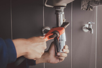 plumber at work in a bathroom, plumbing repair service , fix water plumbing leaks, replace the...