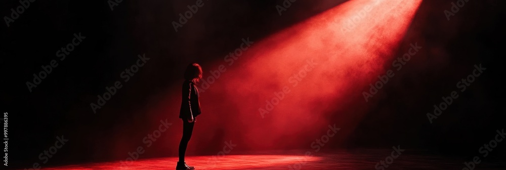 Aufkleber in a dimly lit space, a lone figure is illuminated by a bright red spotlight, creating a dramatic an
