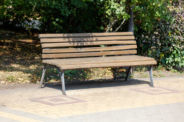 A wooden bench with a brown back and a white seat sits on a brick walkway