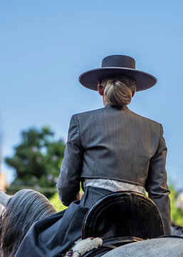 Mujer joven vestida con la tradiciconal indumentaria vaquera de Andaluc&iacute;a, montando a caballo en la feria de Fuengirola, Espa&ntilde;a