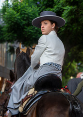 Chica joven con traje y sombrero a la vaquera paseando en caballo por la feria de Fuengirola